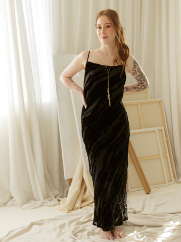 Textured velvet maxi dress with cowl neckline, adjustable spaghetti straps, and slip-style silhouette.