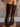 Pair of knee-high faux leather boots with a pointed toe, side zipper, cushioned footbed, and mid block heel.