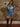 Denim mini dress with long sleeves, pearl snap buttons, floral embroidery, fringe details, and waist belt.
