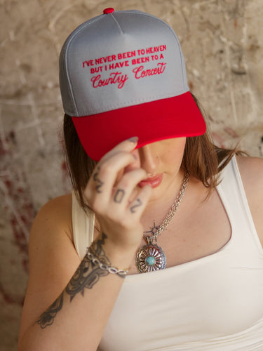 Trucker-style hat with red brim, embroidered front, and plastic adjustable snap closure.