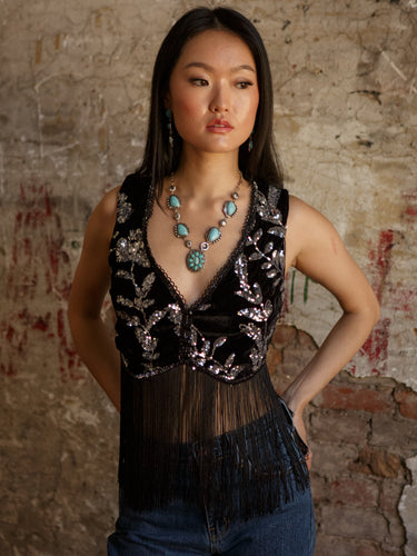 Sleeveless cropped vest with v-neck, sequin detailing, two button accents, fringe, and stretch.