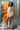 Woman in a floral romper standing in a room with colorful walls and decor.