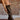 Pair of knee-high faux leather boots with a pointed toe, side zipper, cushioned footbed, and mid block heel.