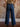 Model wearing mid-rise wide-leg jeans with exposed side seams, a button and zipper closure, and classic 5-pocket design with stretch.