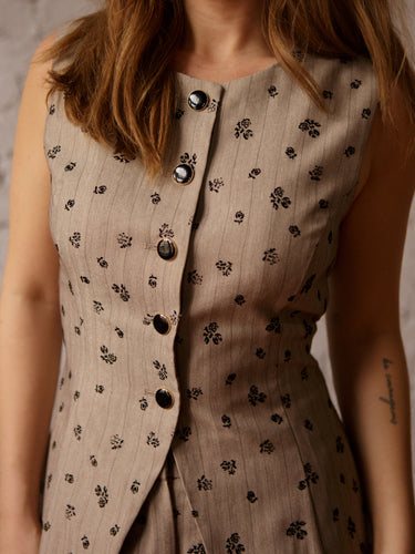 Long sleeveless vest with high neck, button-up front, dainty floral print, and fitted back with gold pin.