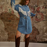 Denim mini dress with long sleeves, pearl snap buttons, floral embroidery, fringe details, and waist belt.
