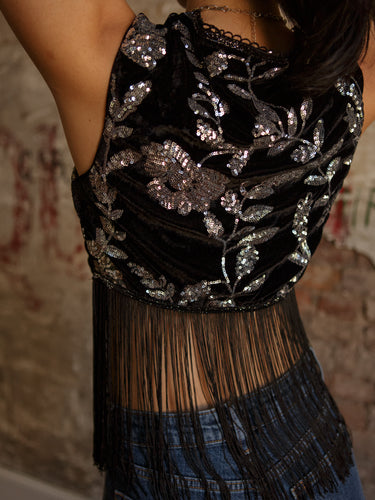 Sleeveless cropped vest with v-neck, sequin detailing, two button accents, fringe, and stretch.